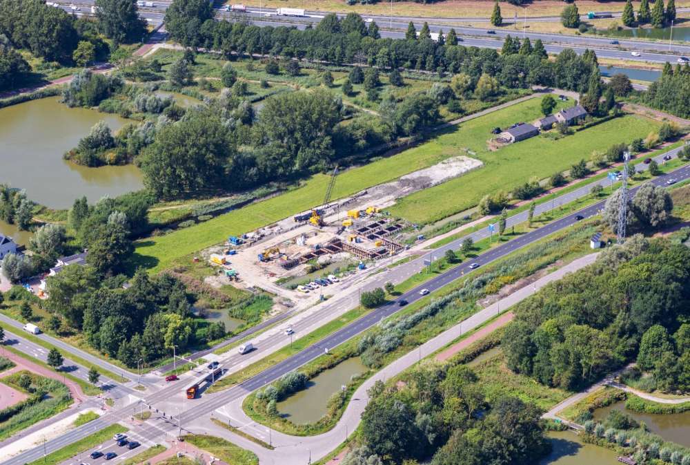 Luchtfoto van een bouwplaats naast een snelweg in een groen landschap bij Rijswijk.
